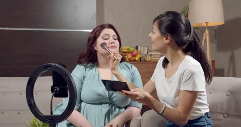 Two young women doing makeup and talking about beauty products while recording Stock Footage 150113073