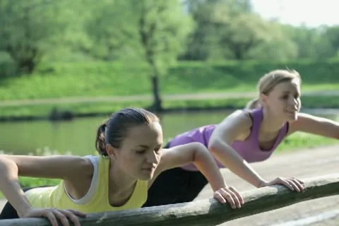 Two young women doing push-ups at the park  NTSC Stock Footage 10963106