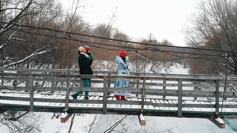 Two young women drinking hot drinks from the thermos and walk on the bridge Stock Footage 126243631