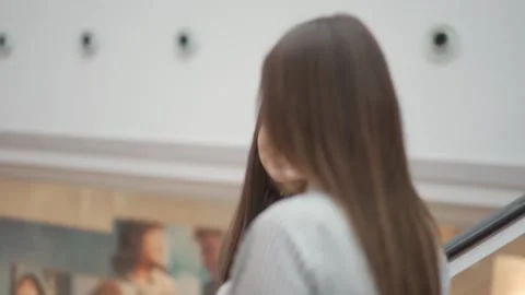 Two young women go down the escalator in the shopping center. 库存影片 144598972