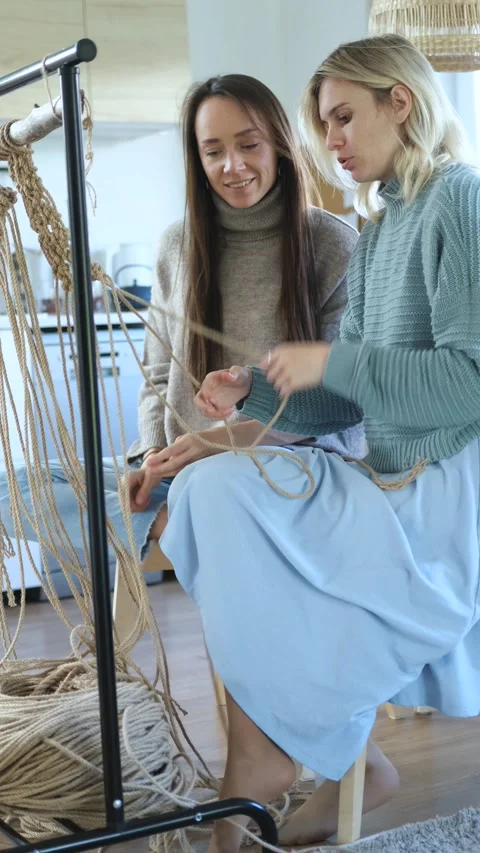 Two young women learn to weave macrame, vertical video Video stock 237709924