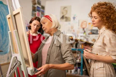 Two young women looking at famous artist painting on canvas Stock Photos