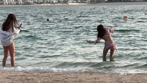 Two young women pose elegantly on a Palm Jumeirah beach, the Persian Gulf's t Stock Footage 313388326