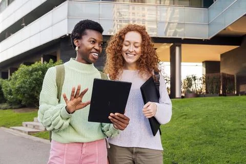 Two young women smiling while using a tablet Stock Photos
