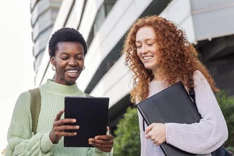 Two young women smiling while using a tablet Stock Photos