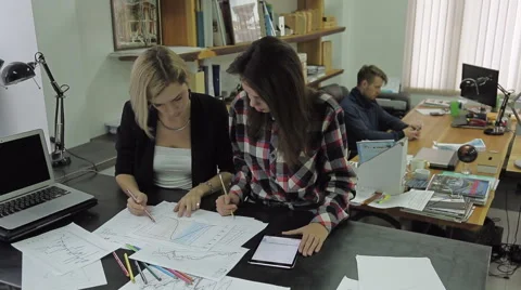 Two young women studying documents in office, behind them a man with a Video stock 62712779