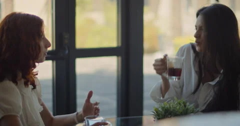 Two young women talking to each other while having a coffee break at work. Sl Stock Footage 146201135