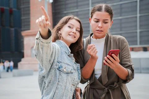Two young women using a map application on a mobile phone to find a location Stock Photos