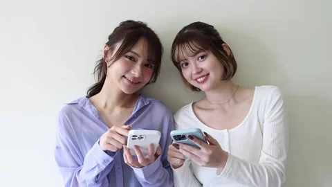 Two Young Women Using Smartphones Together and Sharing Content Stock Footage 344091043