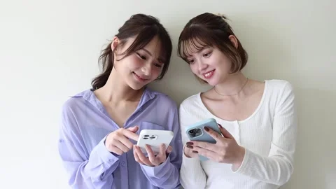 Two Young Women Using Smartphones Together and Sharing Content Stock Footage 344091174