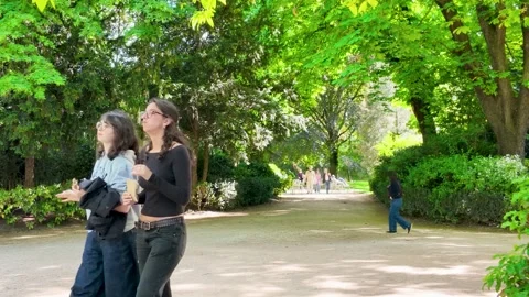 Two Young Women Walking Through a Lush Green Park in Paris Stock Footage 335612720