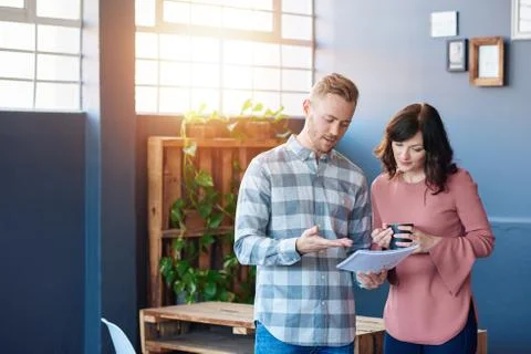 Two young work colleagues discussing paperwork together in an office Stock Photos