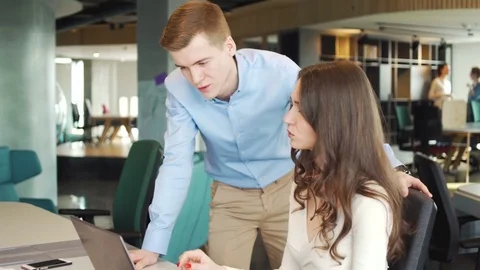 Two young workers discuss business questions using laptop in the office Видео 73522457