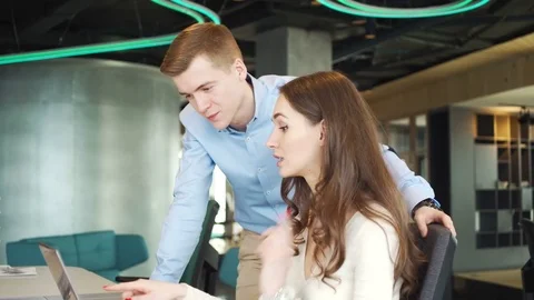 Two young workers discuss business questions using laptop in the office Vidéo 73523002