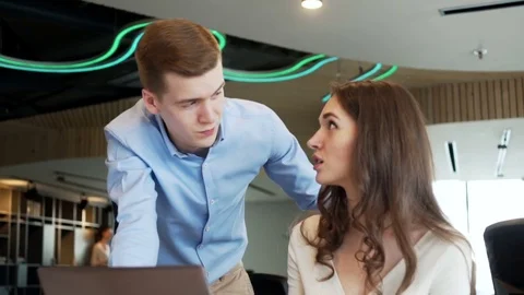 Two young workers discuss business questions using laptop in the office Stock Footage 73523685