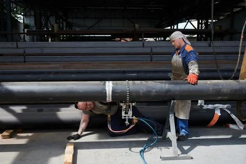 Two young workers in a large diameter pipe warehouse in the process of Stock Photos