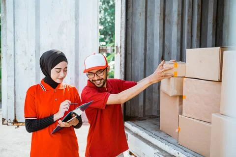 Two young workers in red uniforms manage boxed products Stock Photos