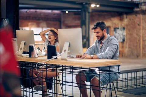 Two young workers, working in modern office in front of desktop computers. Stock Photos
