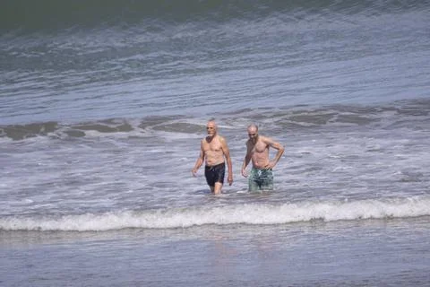 Twoo men taking a bath in the beach Stock Photos
