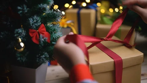 Tying Up Christmas Box Gift Besides Small Christmas Tree Stock Footage 96481186