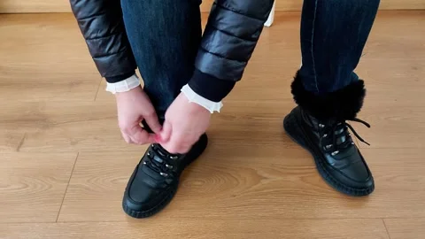 Tying Fur - Lined Black Winter Boots on Wooden Floor Indoors Video stock 328003369