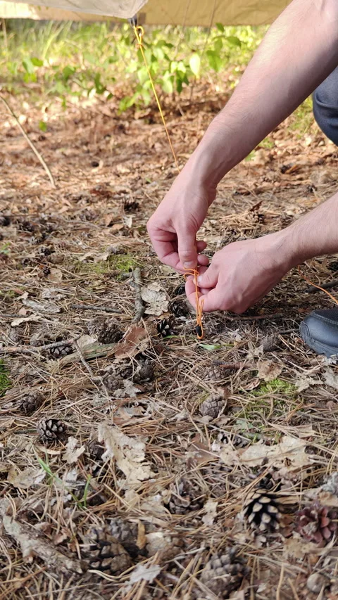 Tying Guyline Cord Around Carbon Tent Stake In Ground Soil Stock Footage 346548870