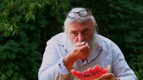 Tylized senior man with beard and glasses on head biting juicy watermelon. Stock Footage 328357359