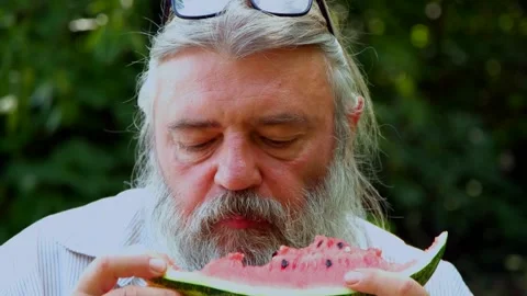 Tylized senior man with beard and glasses on head biting juicy watermelon. Stock Footage 328357361