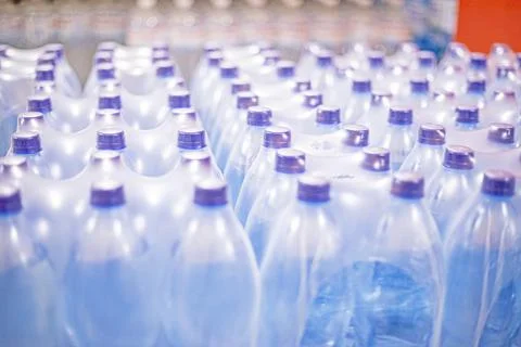 Types of drinking water in plastic bottles in packs at the supermarket. Hea.. Stock Photos