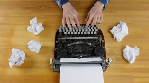 Typewriter and crumpled sheets of paper on a wooden table. Male hands type on Stock Footage 99364520