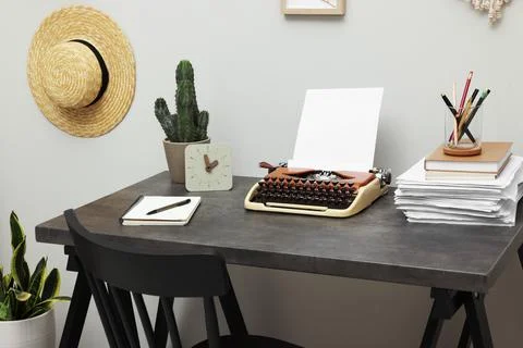 Typewriter and stack of papers on dark table in room. Writer's workplace 스톡 사진