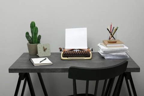 Typewriter and stack of papers on dark table near light grey wall. Writer's.. 스톡 사진