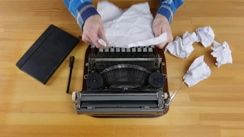 Typewriter, notebook and crumpled sheets of paper on a wooden table. Male han Stock Footage 99364334