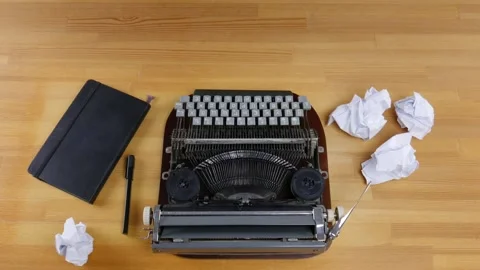 Typewriter, notebook and crumpled sheets of paper on a wooden table. Male han Stock Footage 99364911