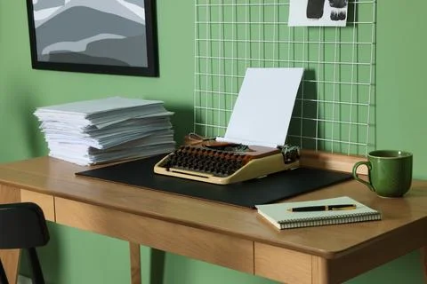 Typewriter, stack of papers and mood board on wooden table near pale green .. 스톡 사진