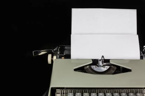 Typewriter on the table on a black background with white paper with empty space Stock Photos