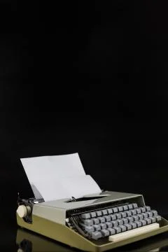 Typewriter on the table on a black background with white paper with empty space Stock Photos
