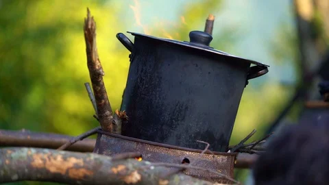 Typical boyscout cocking in the woods adjusting fire Stock Footage 123413735