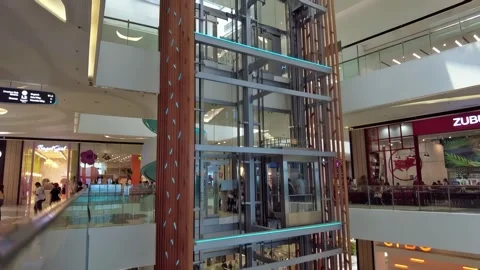 A typical glass-walled elevator affords visitors at a Philippine mall a vast Stock Footage 345680762