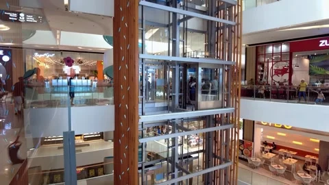 A typical glass-walled elevator affords visitors at a Philippine mall a vast Stock Footage 345680923