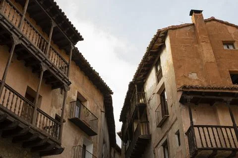 Typical orange-colored adobe facades with wooden balconies in the medieval .. Stock Photos