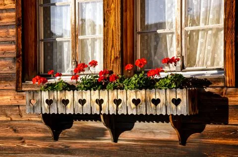Typical red geranium flowers in the windows of traditional Alpine wooden chalets Stock Photos