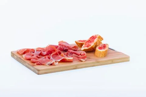 Typical spanish ham next to some tomato-rubbed bread slices on a wooden cutti Stock Photos