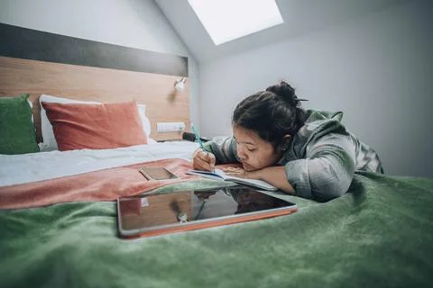 Typical study moment where a student uses both her tablet and notebook, set in a Stock Photos