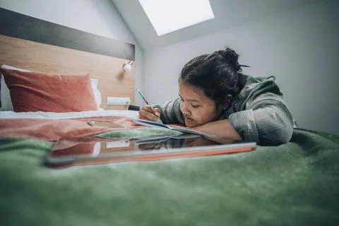 Typical study moment where a student uses both her tablet and notebook, set in a Stock Photos