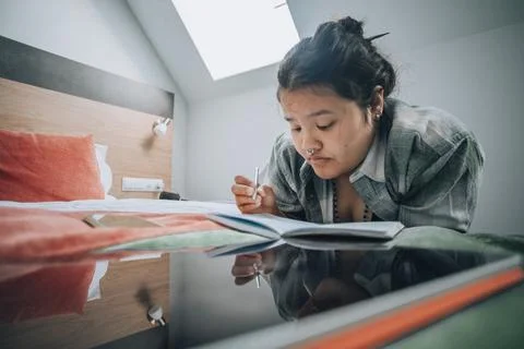 Typical study moment where a student uses both her tablet and notebook, set in a Stock Photos