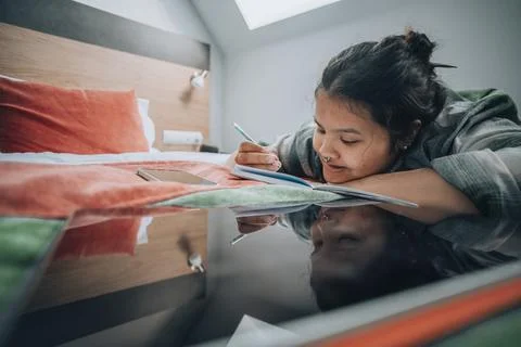 Typical study moment where student uses both her tablet and notebook, set in a Stock Photos