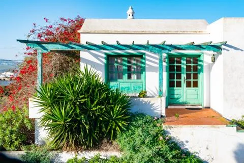 Typical tiny Canarian house with cactus garden and green doors or windows on  Stock Photos