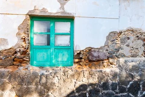 Typical tiny Canarian house with cactus garden and green doors or windows on  Stock Photos