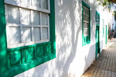 Typical tiny Canarian house with cactus garden and green doors or windows on  Stock Photos